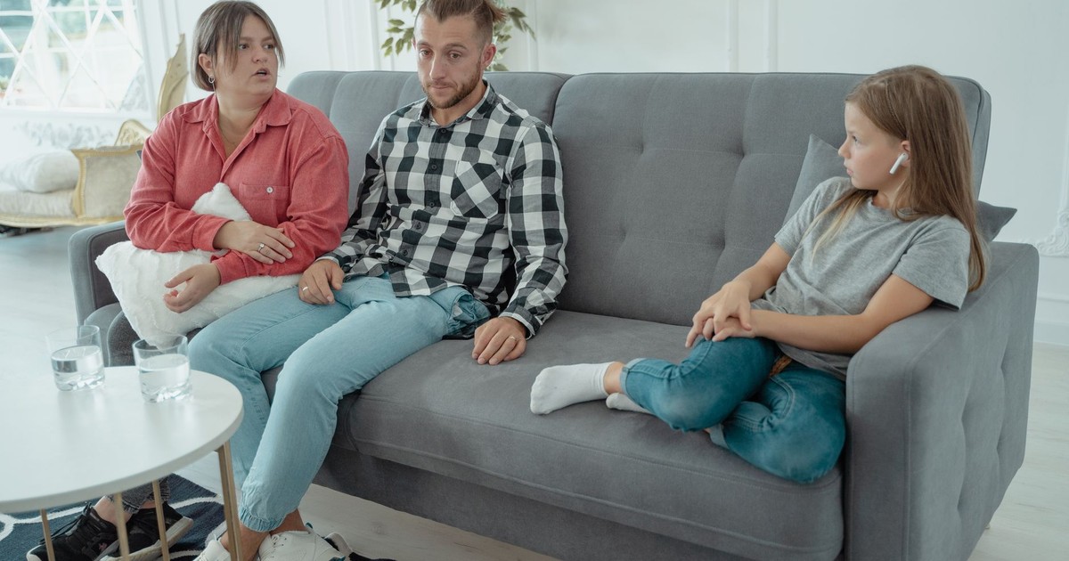 A family sits together on a sofa, discussing in a comfortable home setting, indicating a counseling session.
