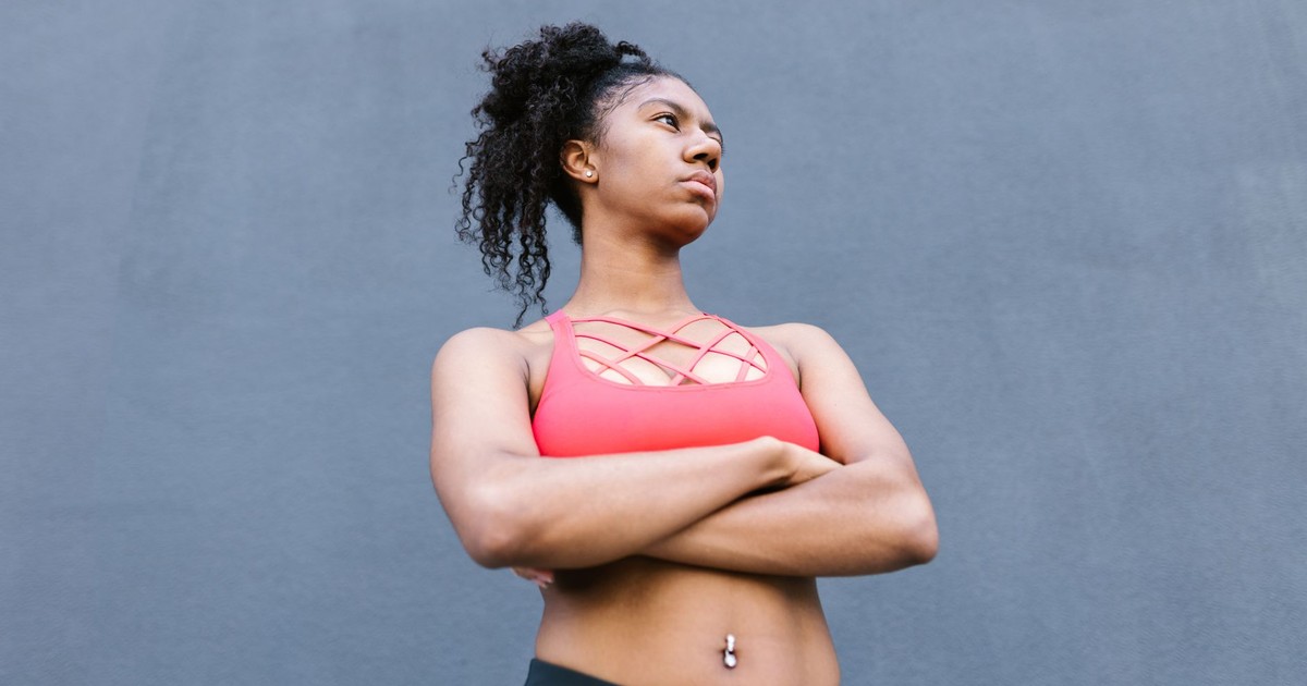 Strong woman with afro hair poses confidently in sportswear, showcasing empowerment and fitness goals.