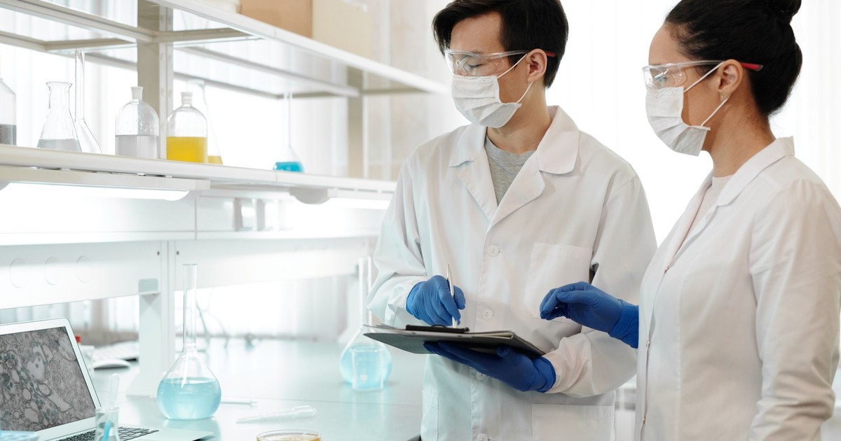 Researchers in laboratory wearing masks, gloves, and goggles working on scientific experiments.
