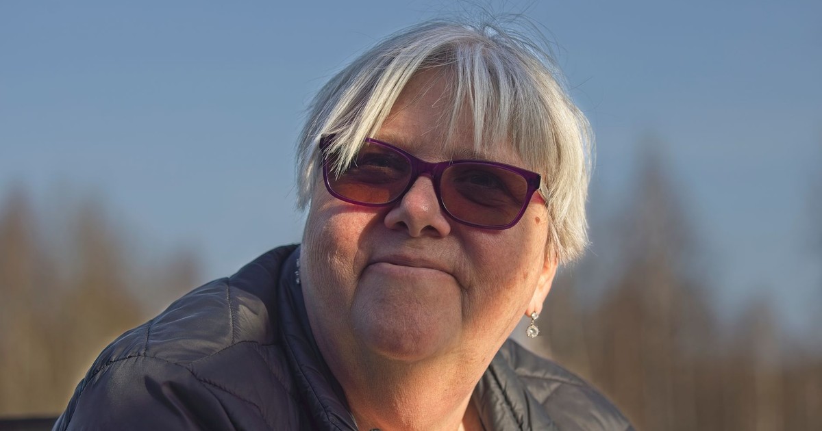 Portrait of a senior woman with gray hair and sunglasses in the sunlight, looking content outdoors.