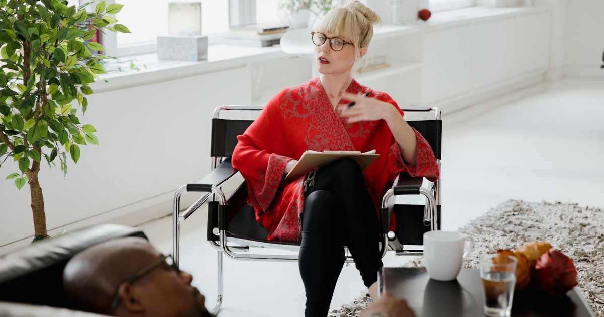 A therapist consults with a patient in a bright, modern office setting.