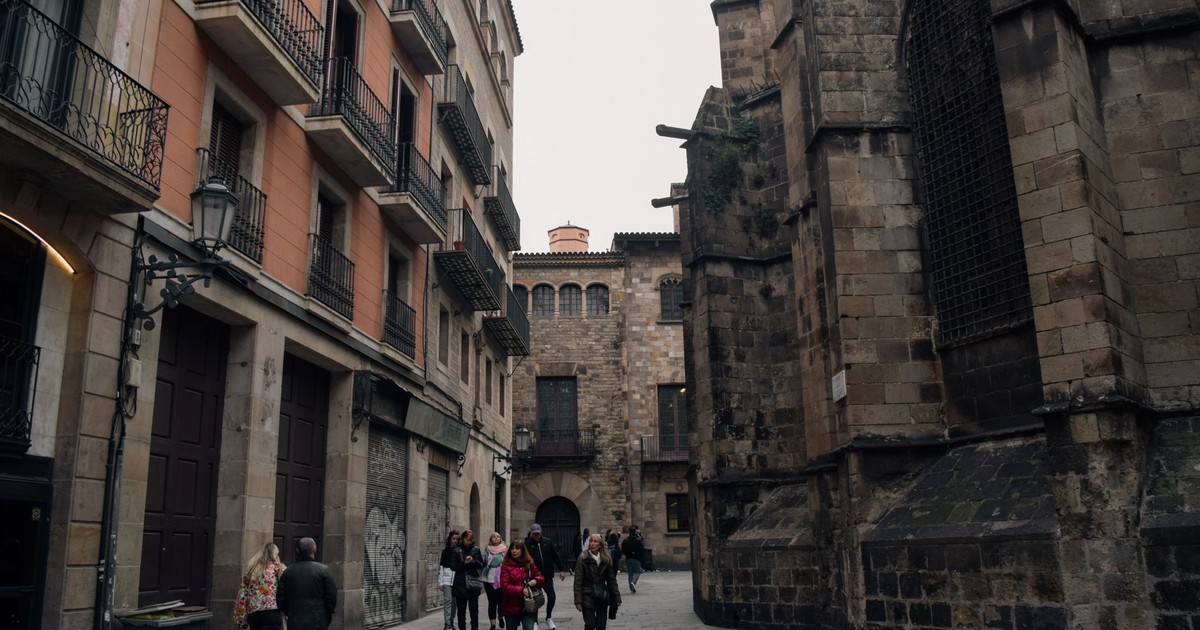 A bustling alley in Barcelona filled with people against historic buildings' backdrop.