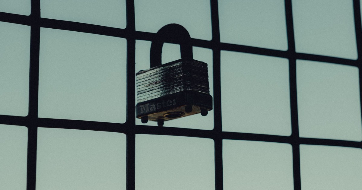 Close-up of a steel padlock on a mesh fence, symbolizing protection and security.