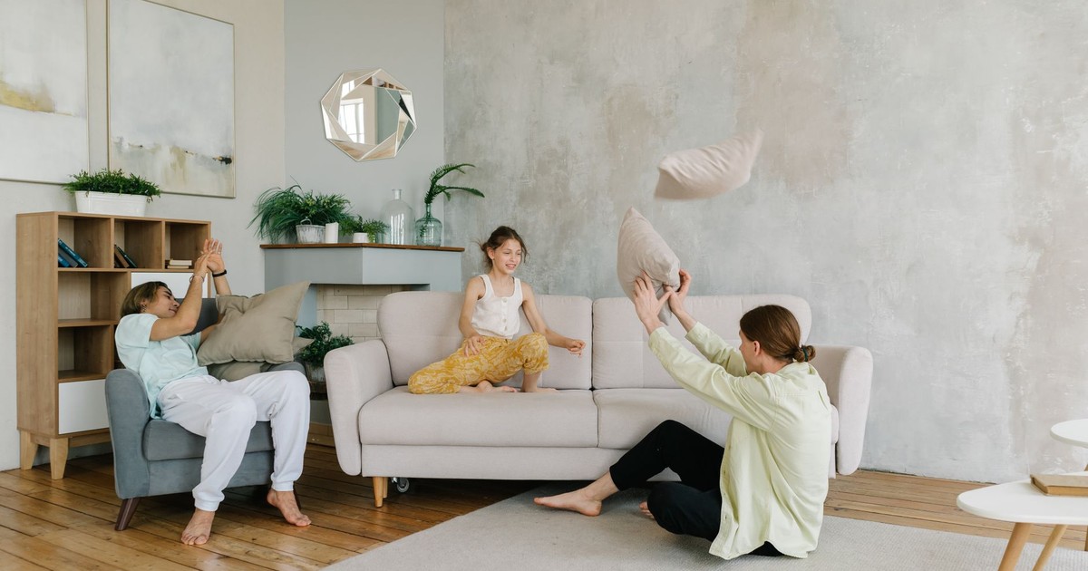 A happy family enjoying playful bonding time at home by tossing pillows in a cozy living room.