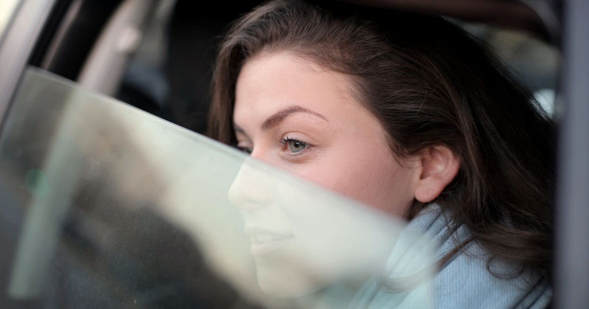 A woman gazes thoughtfully out a car window, capturing a moment of reflection and travel.