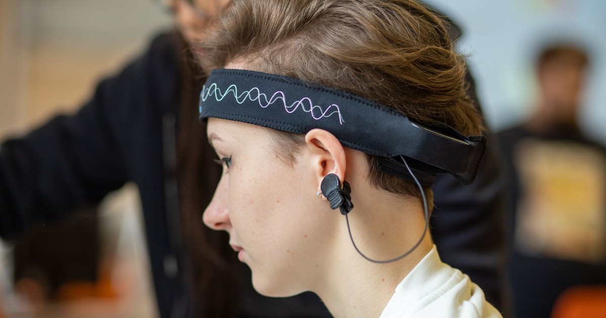 Close-up of a young woman wearing an EEG headband, showcasing modern technology indoors.
