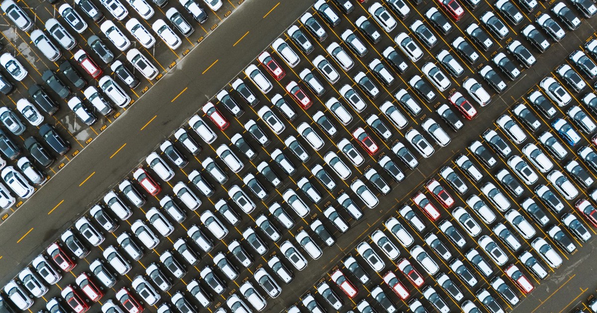 Aerial perspective of neatly parked cars in a large parking lot.