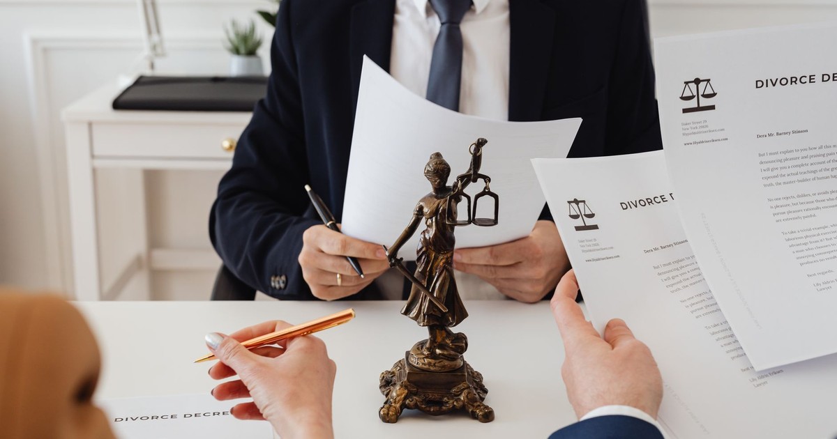Legal professionals reviewing divorce documents in a law office with a Lady Justice statue.