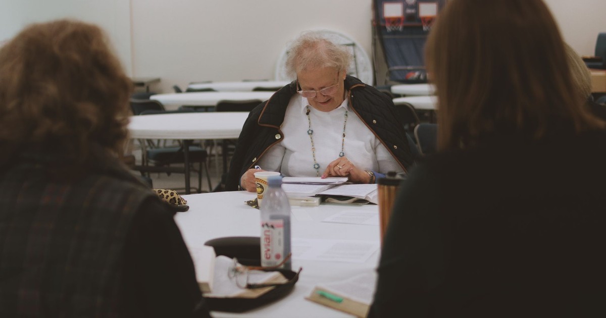 Older women engaging in a Bible study community group session indoors.