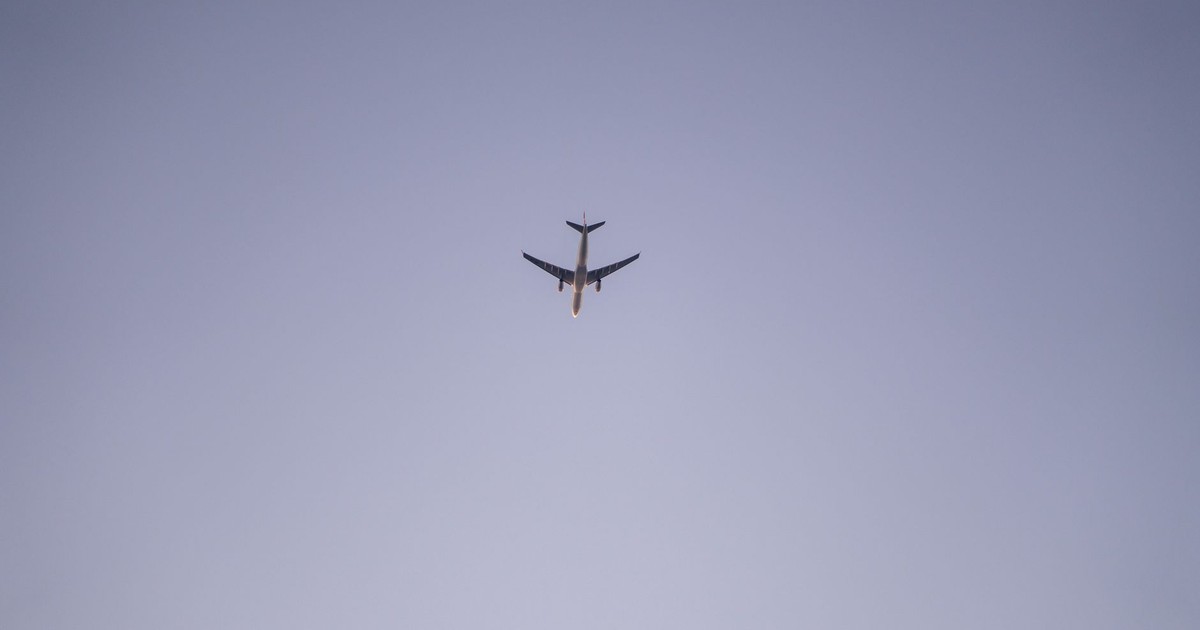 A passenger airplane flying high above, captured against a clear blue sky, showcasing aviation beauty.