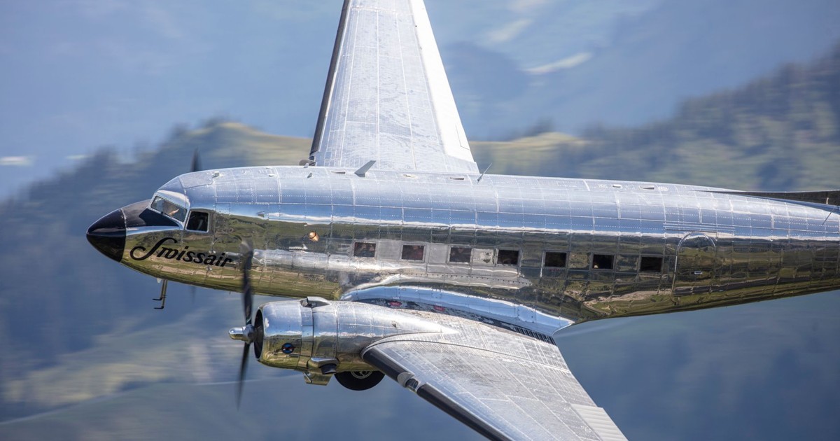 A classic Swissair aircraft flying above the scenic Swiss Alps in clear daylight.