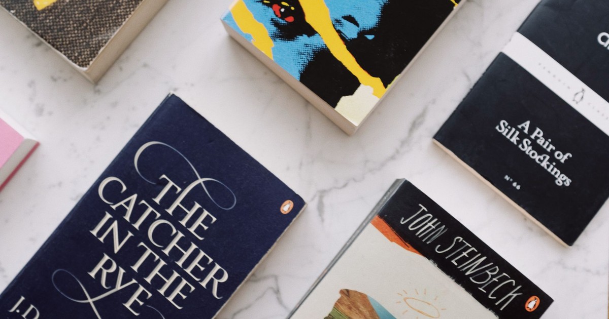 From above of composed colorful paperback novels with colorful covers and inscriptions placed in rows on white marble surface