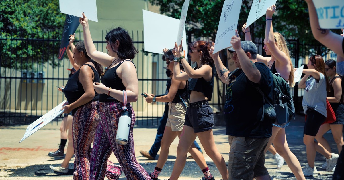 A diverse group of activists protesting outdoors, holding placards and engaging in social activism.