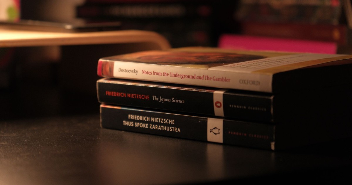 Stack of classic books by Dostoevsky and Nietzsche on a dark desk.