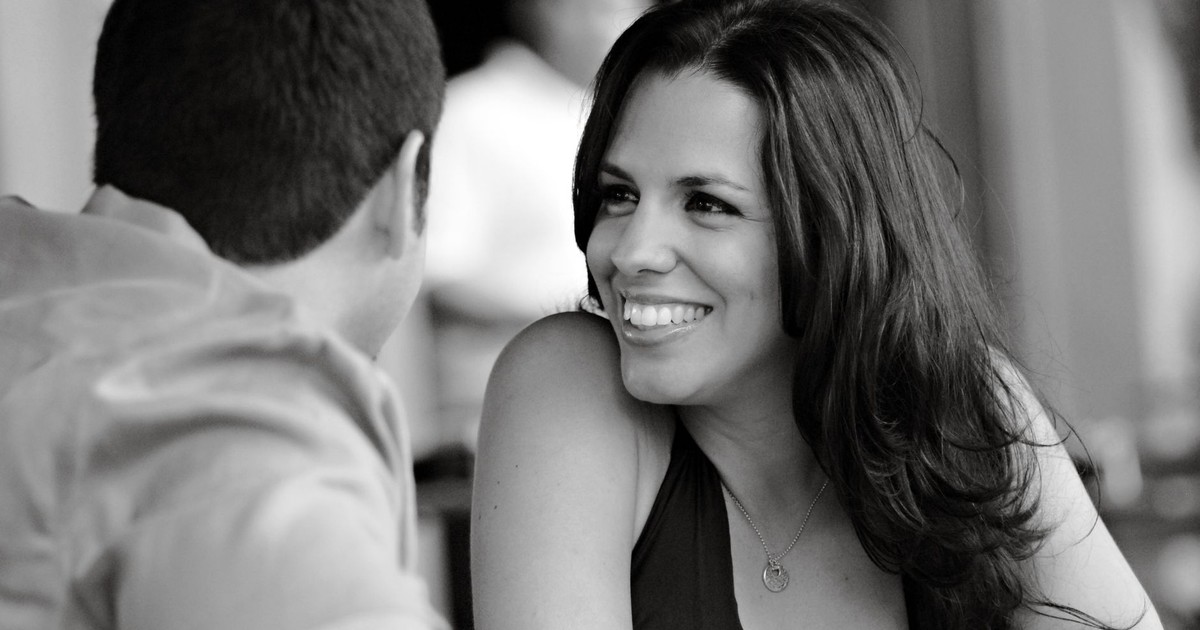 Charming black and white image of a woman smiling at a café table, capturing a candid moment.