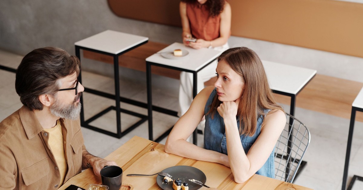 A man and woman engage in conversation over breakfast at a stylish coffee shop.