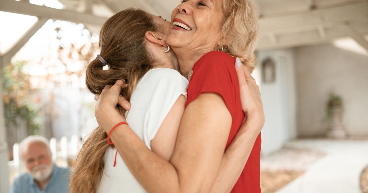 Heartwarming moment of two women sharing a joyful hug outdoors.