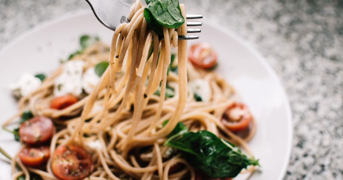 Delicious whole wheat pasta with fresh spinach, cherry tomatoes, and feta cheese in a close-up shot.