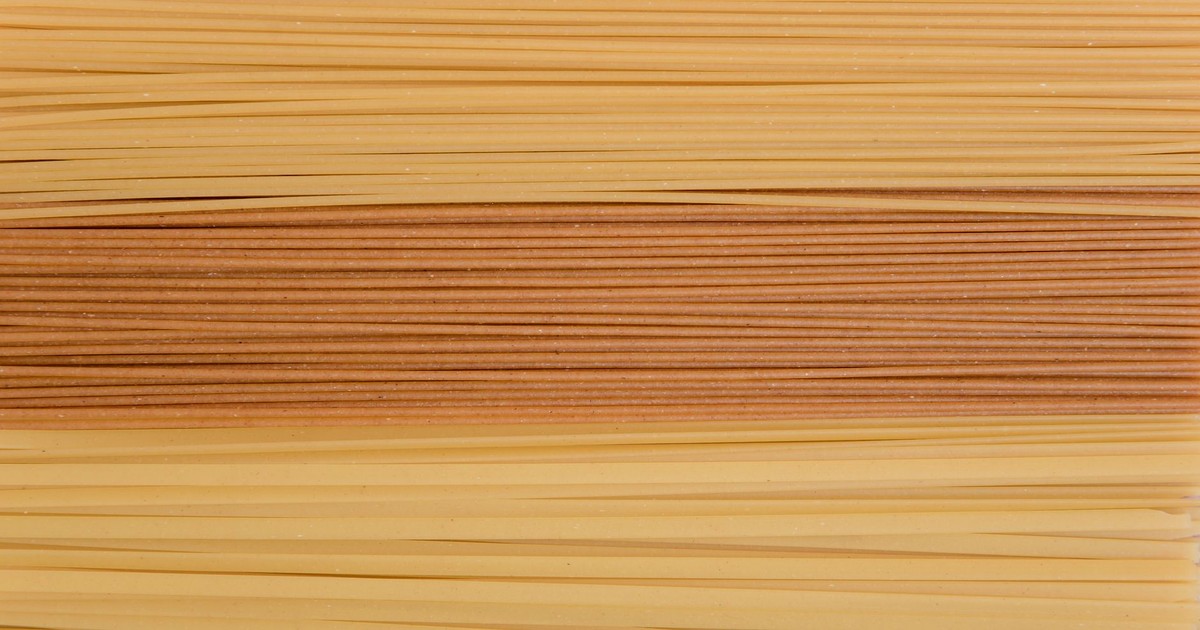 Detailed close-up of stacked uncooked pasta in various shades, showcasing texture.
