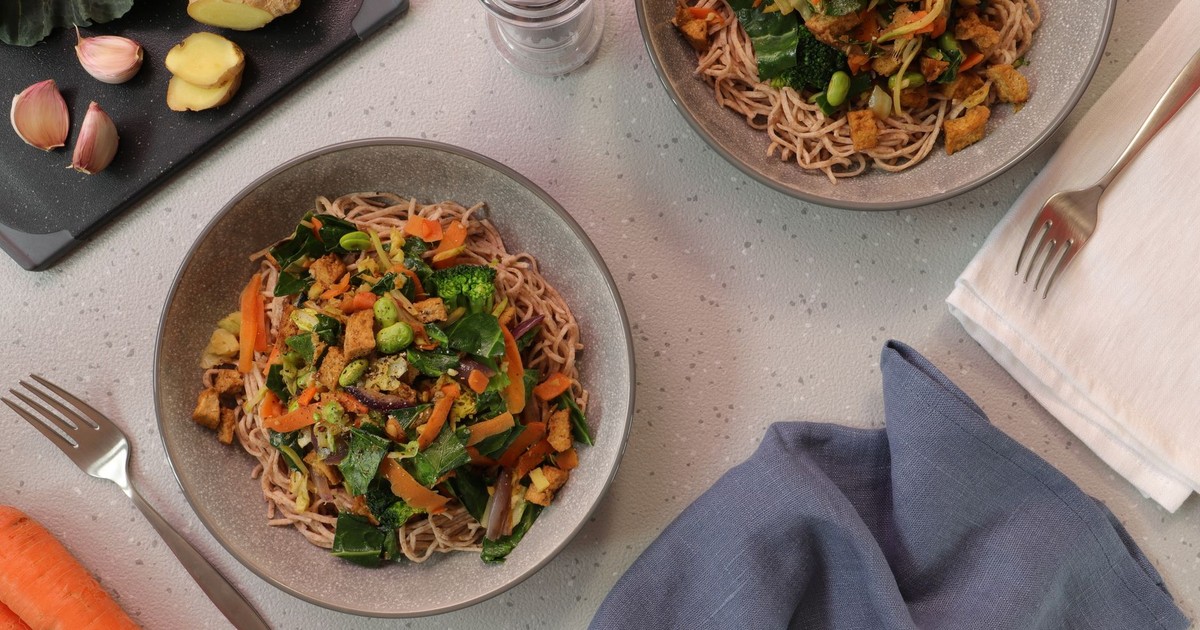 Top-down view of delicious vegetarian noodle bowls garnished with fresh vegetables.