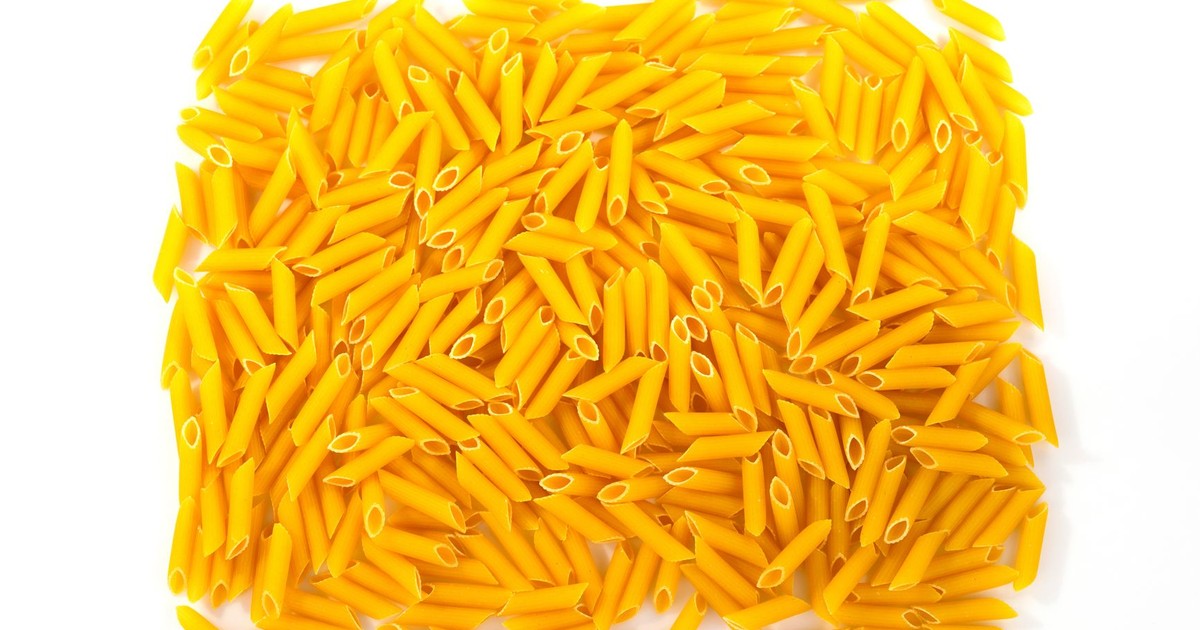 Close-up of uncooked penne pasta arranged on a white background, perfect for food-related designs.