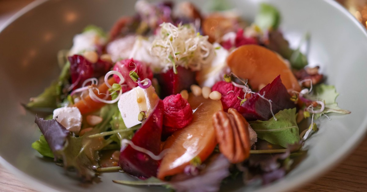 A colorful salad featuring mixed greens, goat cheese, pecans, and vibrant beets.