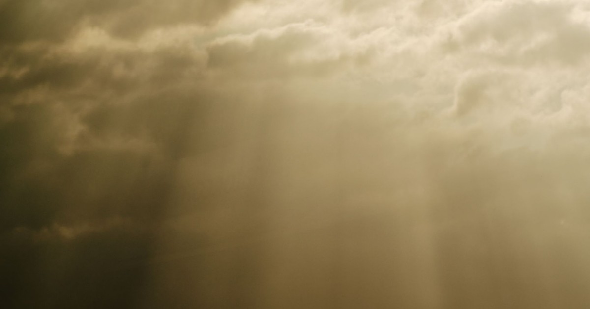 Sun rays piercing through dramatic cloudscape, creating a powerful and serene natural scene.