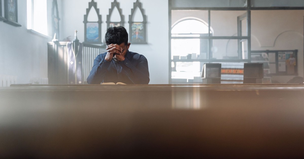 A man in prayer in a sunlit room, reflecting spirituality and peace.