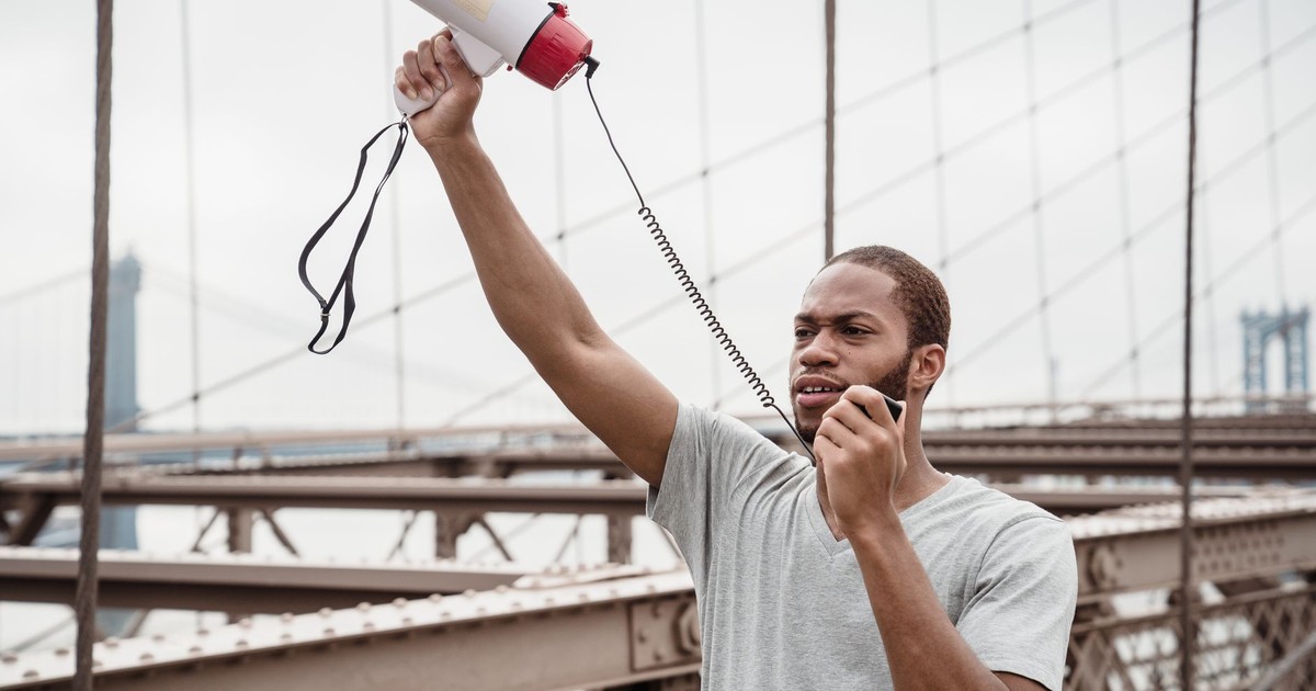 A man passionately protests with a megaphone on a famous bridge.