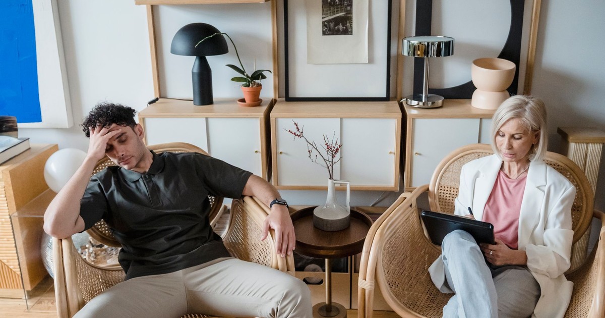 A stressed man and woman therapist in a modern consultation room.