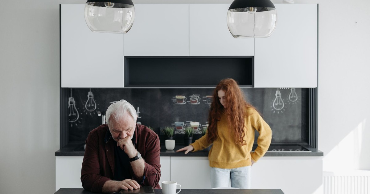An emotional scene of a senior man and a young woman in a modern kitchen, capturing sorrow and family bond.
