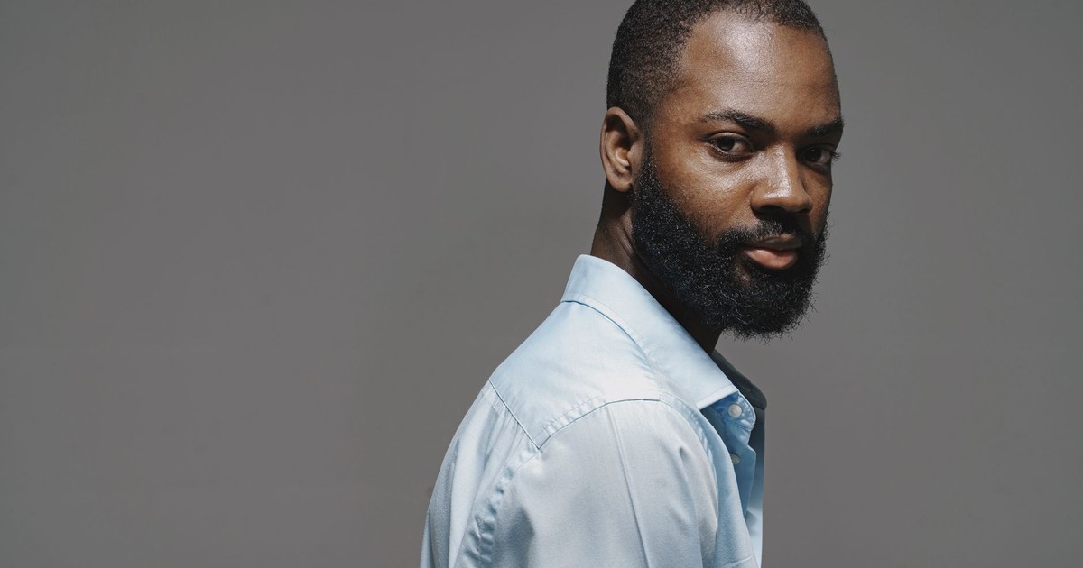 Elegant studio portrait of a well-groomed man in a blue shirt with a contemplative expression.