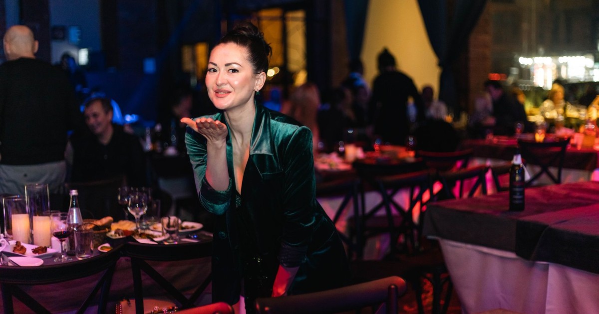 Woman in velvet dress at an indoor celebration with ambient lighting.