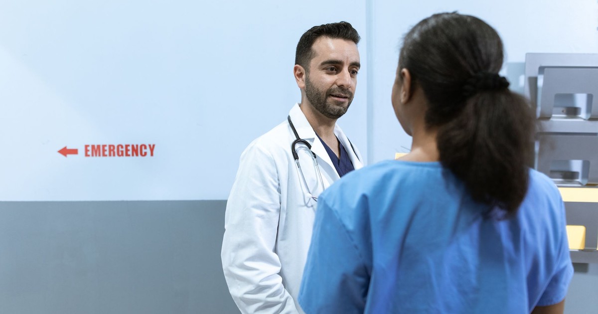 Doctors and nurses conversing near emergency room in a hospital setting.