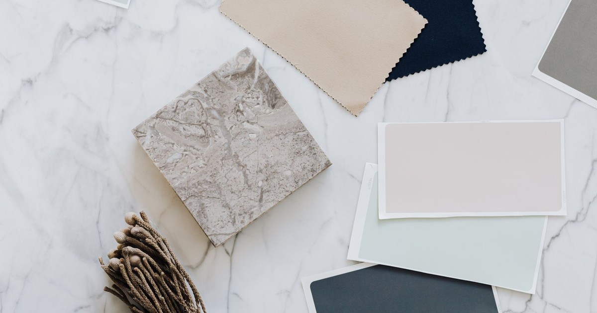 An artistic flat lay showcasing diverse fabric and material samples on a marble surface, emphasizing neutral tones and textures.