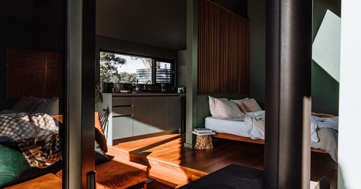 A modern cabin interior featuring wooden floors, cozy furniture, and abundant natural light.