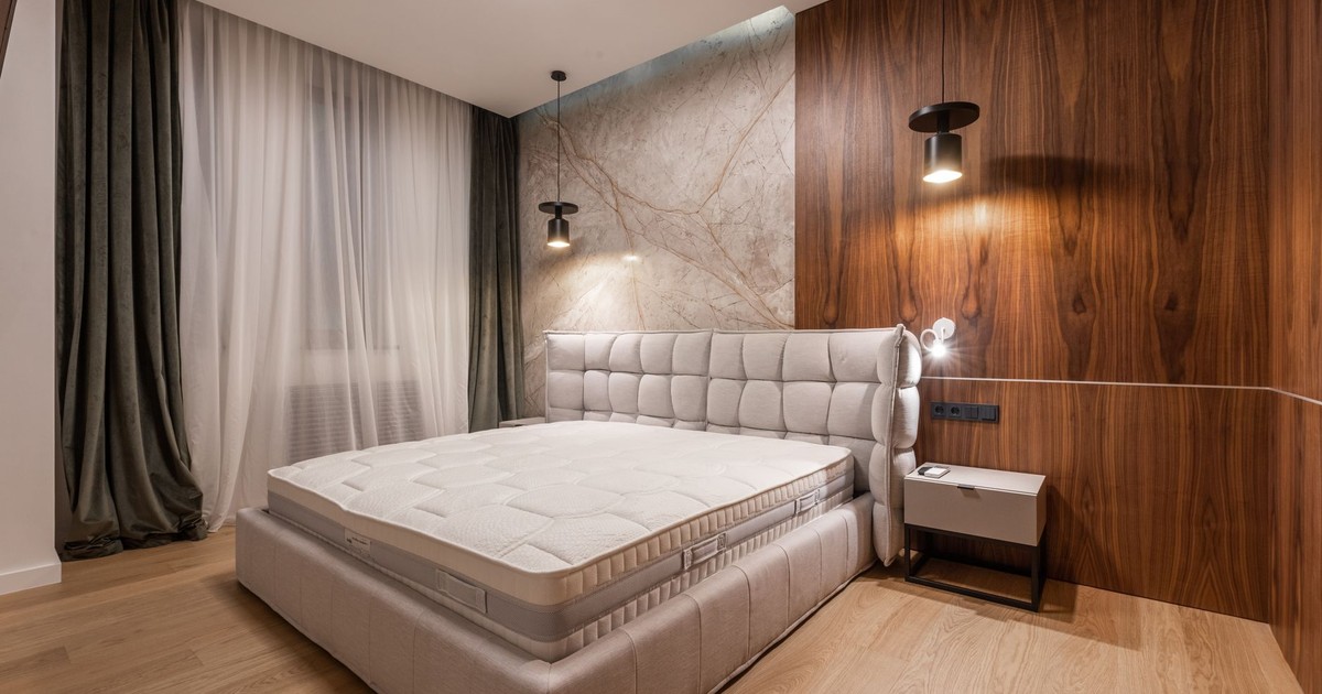 Comfortable soft empty bed placed in stylish modern bedroom in contemporary apartment in minimalistic style