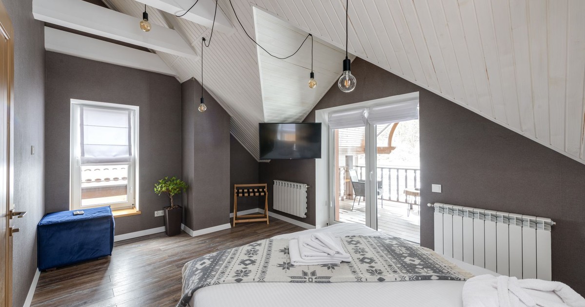A modern bedroom with a large bed, balcony access, and stylish lighting.