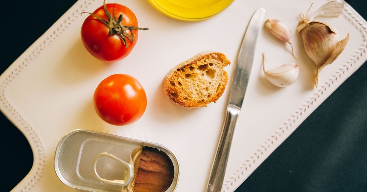 Tomatoes, bread, and sardines arranged for Catalán toast preparation.