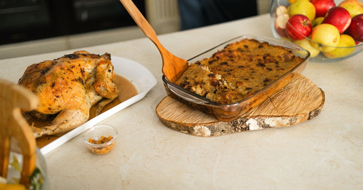 Appetizing roasted chicken served with homemade stuffing and fresh fruits on a table.