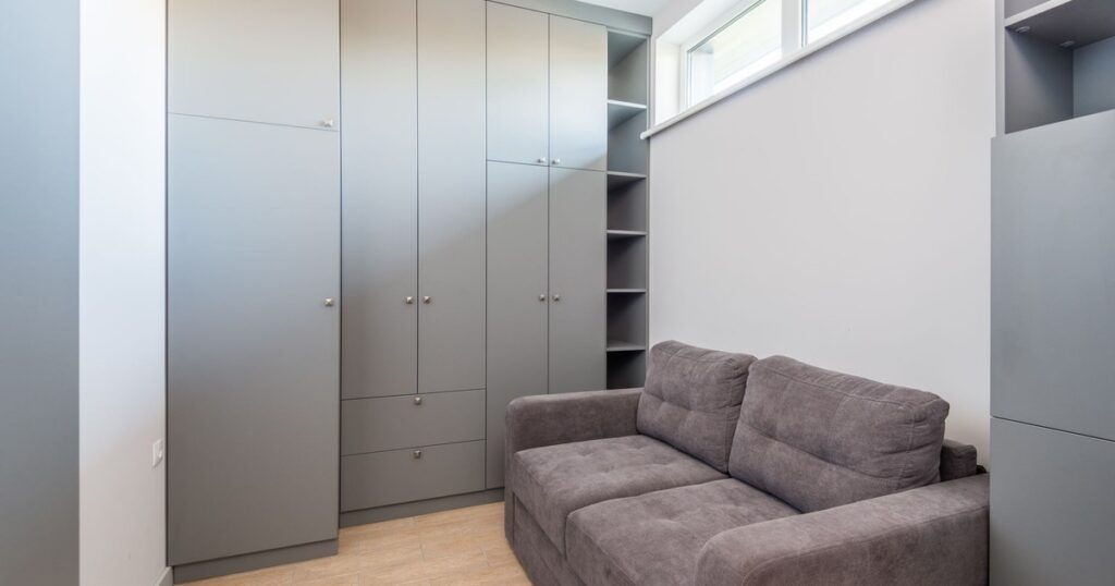 Sleek and modern apartment interior featuring grey wardrobe and sofa, ideal for space-saving living.