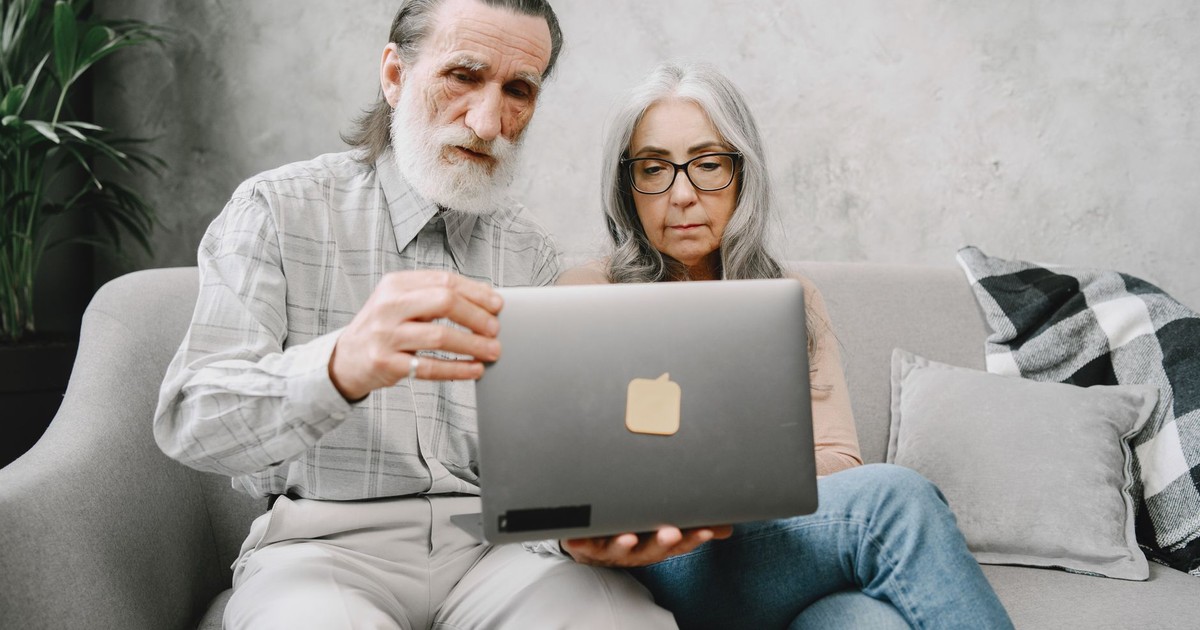 Senior couple engaging with laptop at home, highlighting technology use among elderly.