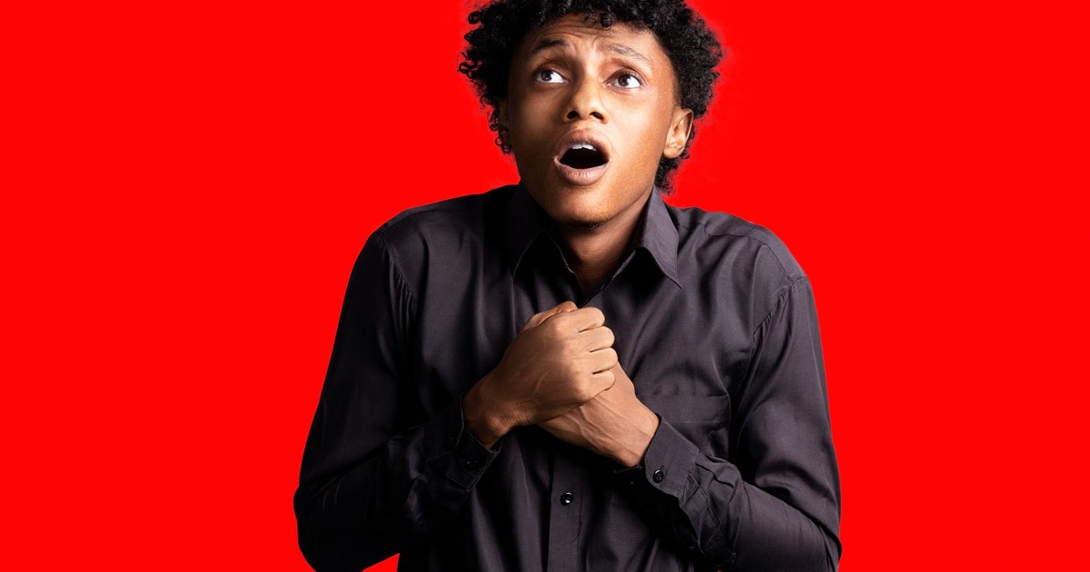 Portrait of a frightened man with open mouth on a red background.