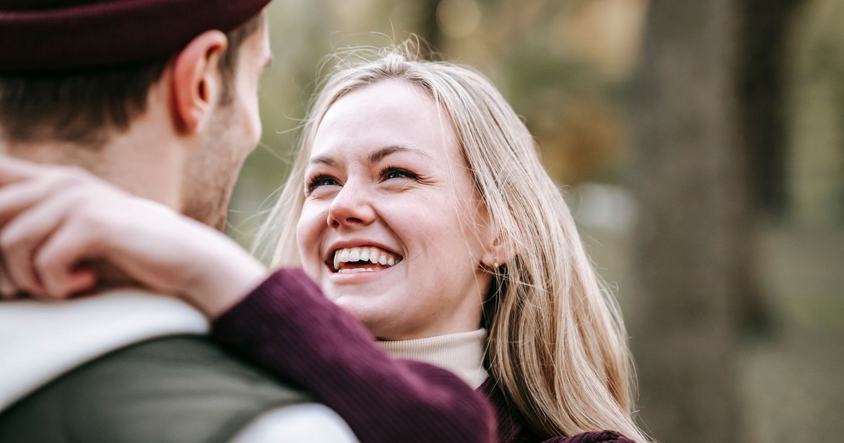 Young positive blond female embracing crop anonymous male partner while looking at each other and spending time together on weekend