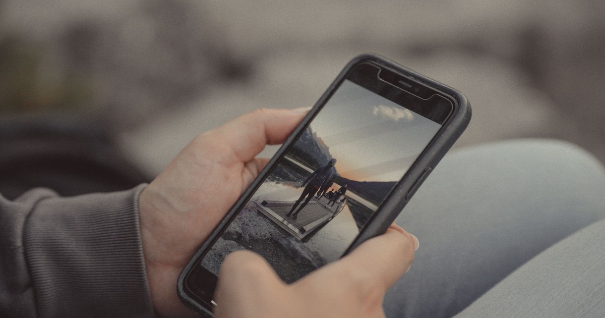 Close-up of hands holding a smartphone showing a mountain scene, captured outdoors in Banff.