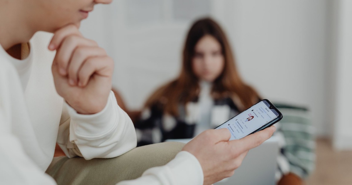 Teens using smartphones indoors with a blurred background, suggesting social media engagement.
