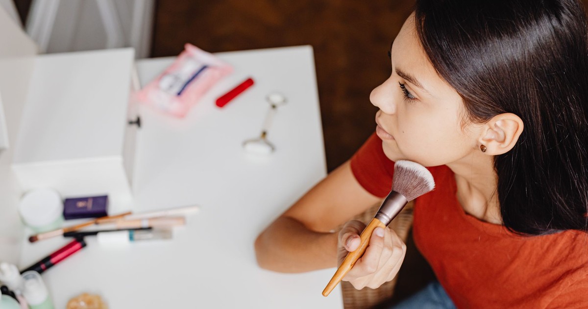 Top view of a woman applying makeup with a brush at a vanity table.