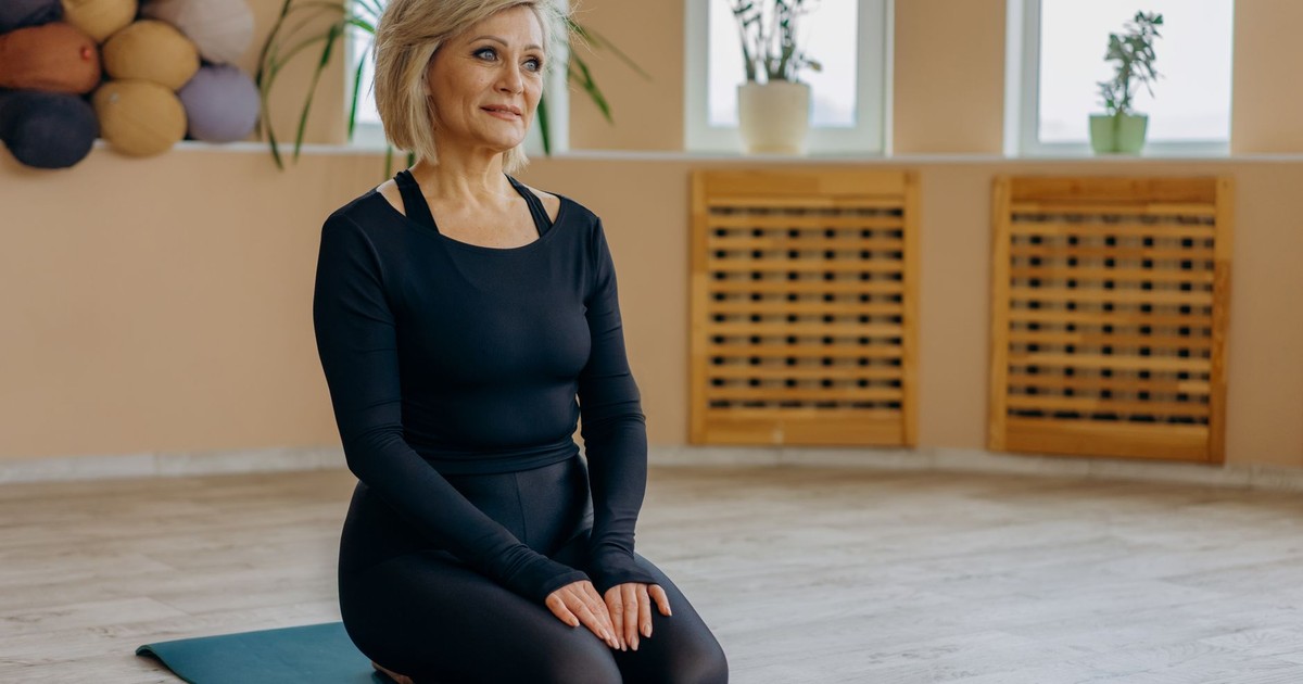 Elderly woman on yoga mat practicing mindfulness and relaxation.
