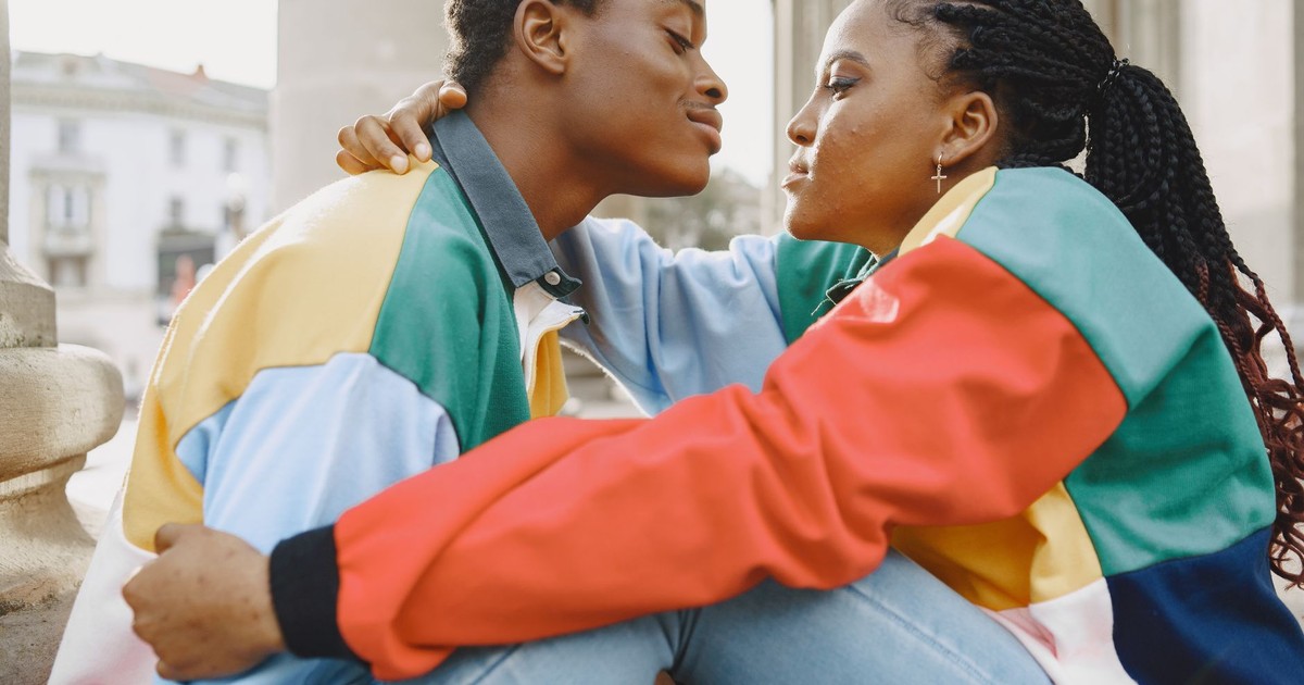 A couple tenderly looking at each other, embracing outdoors on a sunny day.