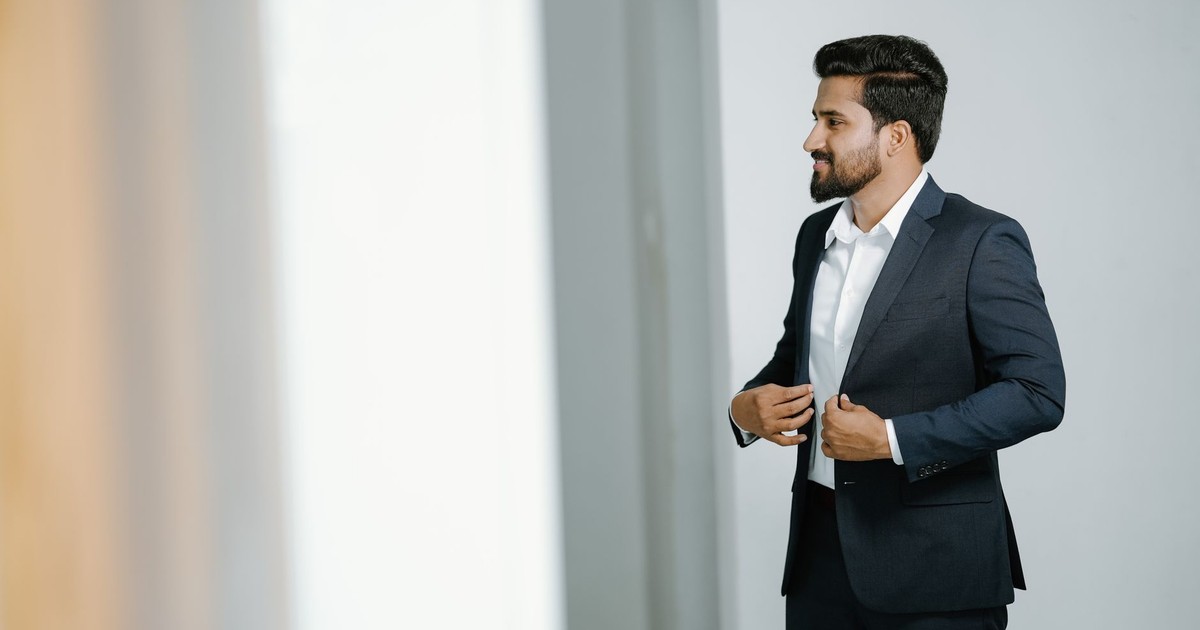 Businessman adjusting his suit indoors, exuding confidence and professionalism in KL, India.